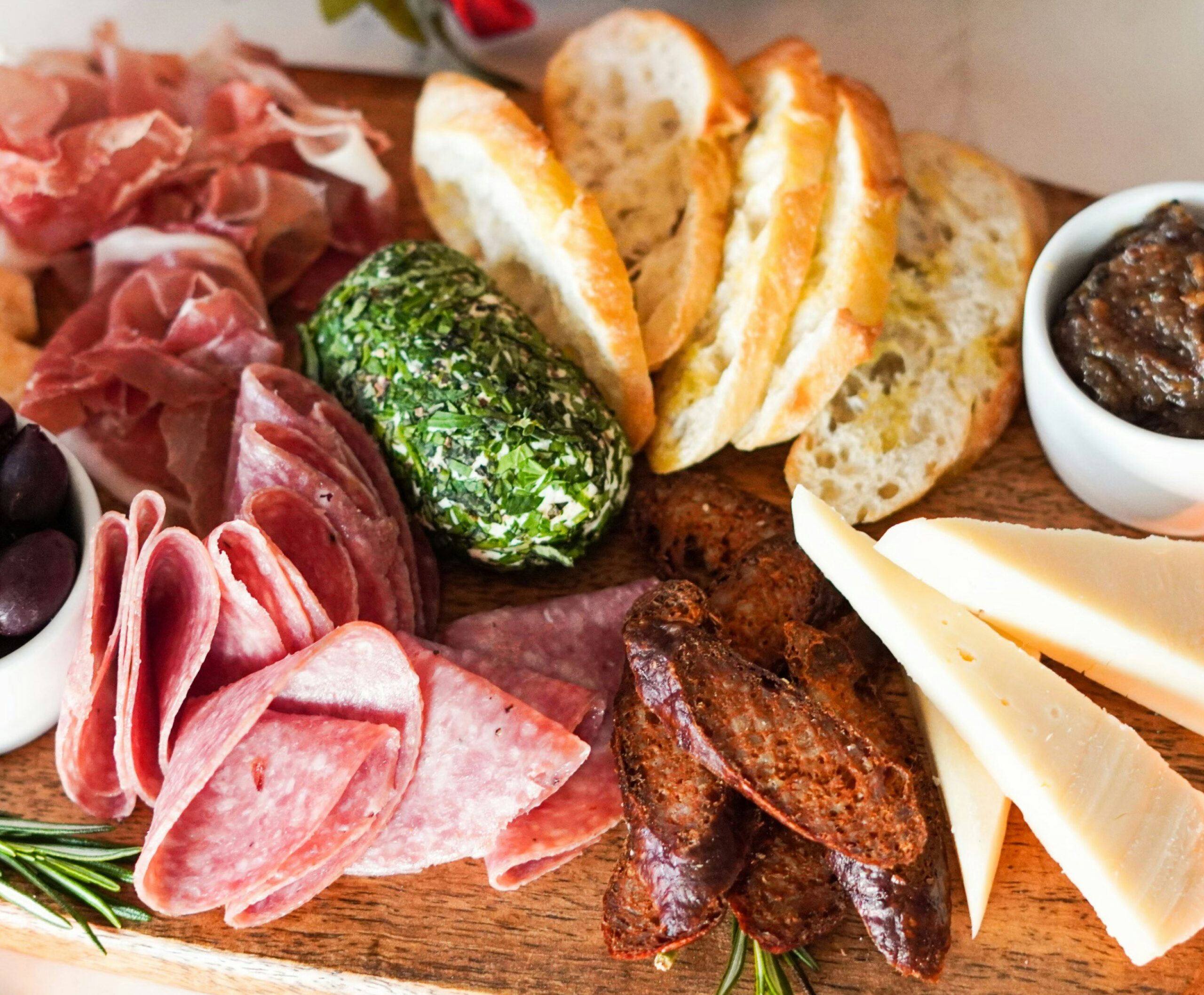 Close up of a charcuterie board with meats, bread, cheese, and accoutrements