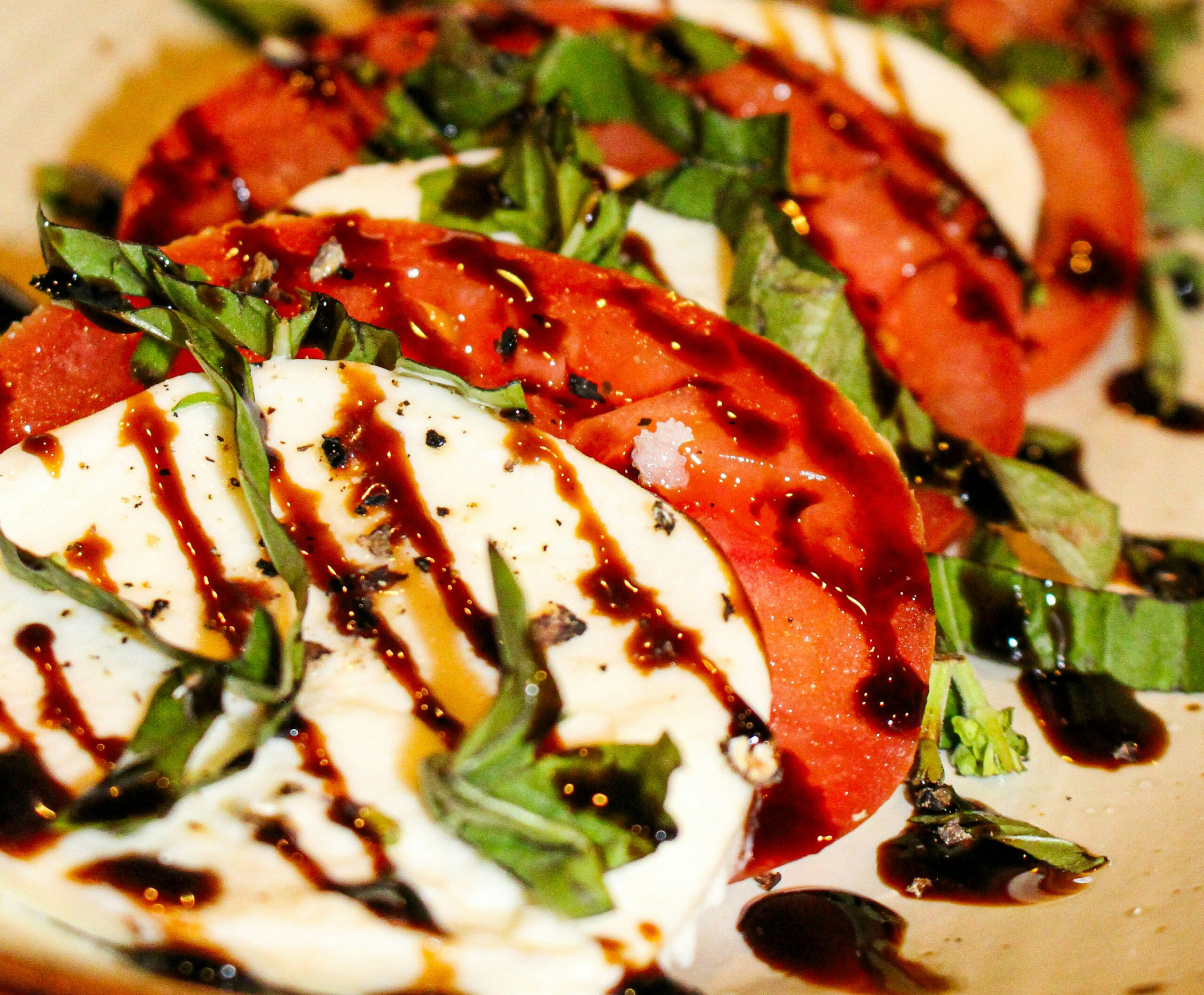 Close up of layers of white and red tortillas with greens and sauce drizzle