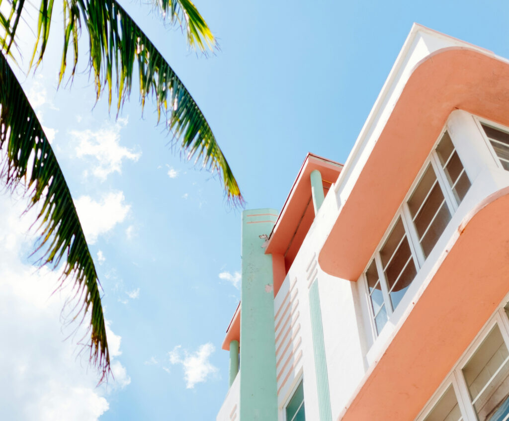 Semi abstract view looking up at underside of modern art deco building with palm fronds with blue sky
