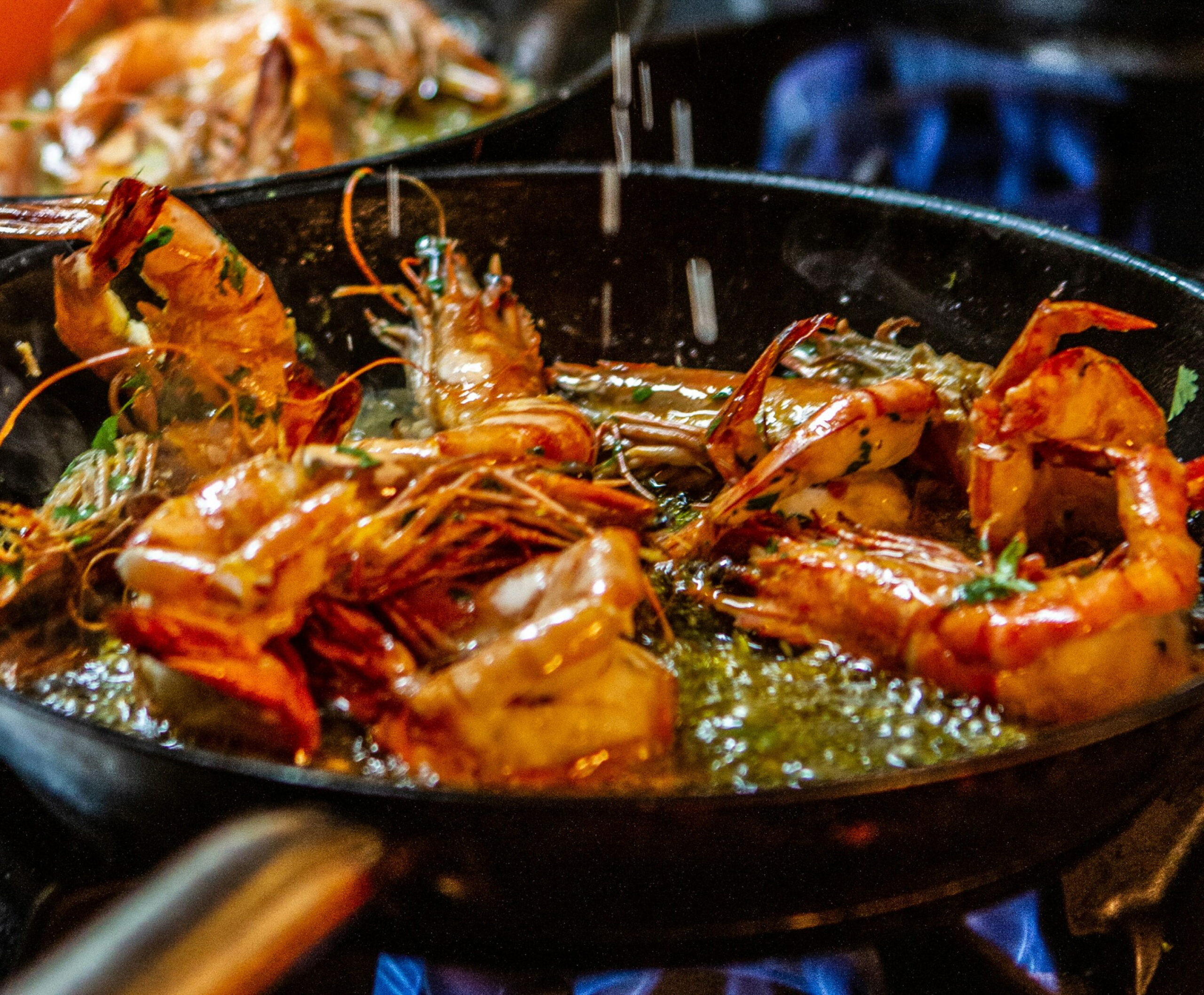 Close up of prawns being sautéed in iron saucepan