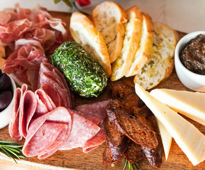 Close up of a charcuterie board with meats, bread, cheese, and accoutrements