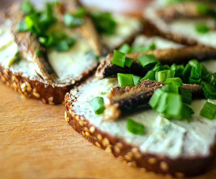 Close up of toast with spread and spring onions on a wood board