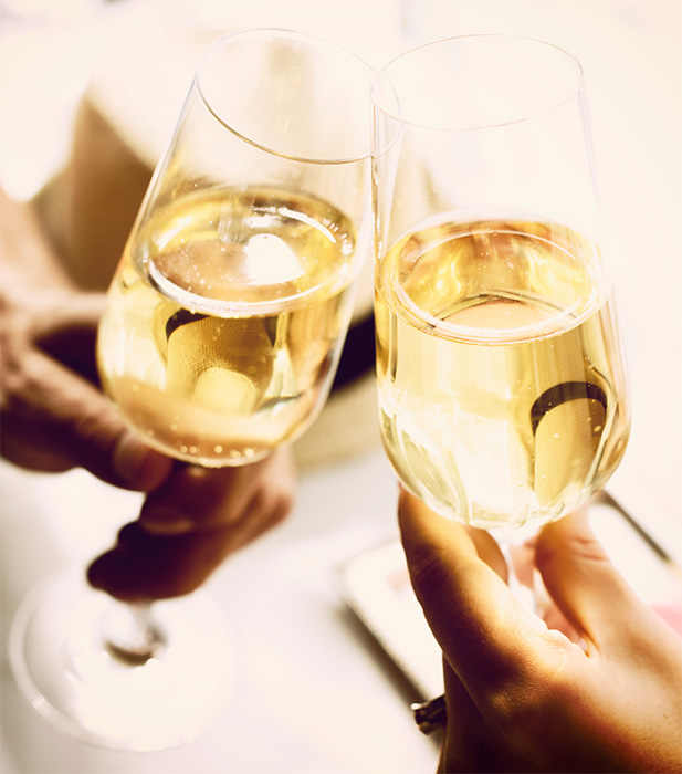 Two flutes filled with prosecco held by two hands in a toast