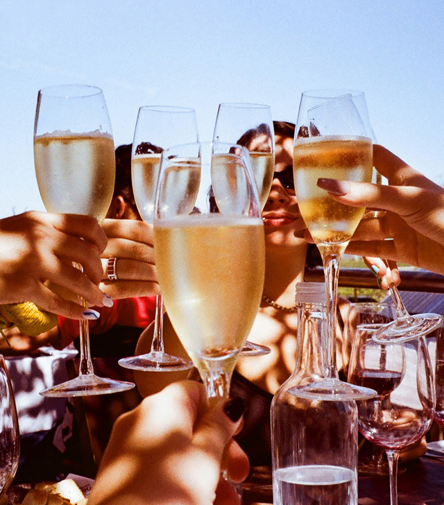Sunny scene of many hands making a toast with flutes filled with Prosecco